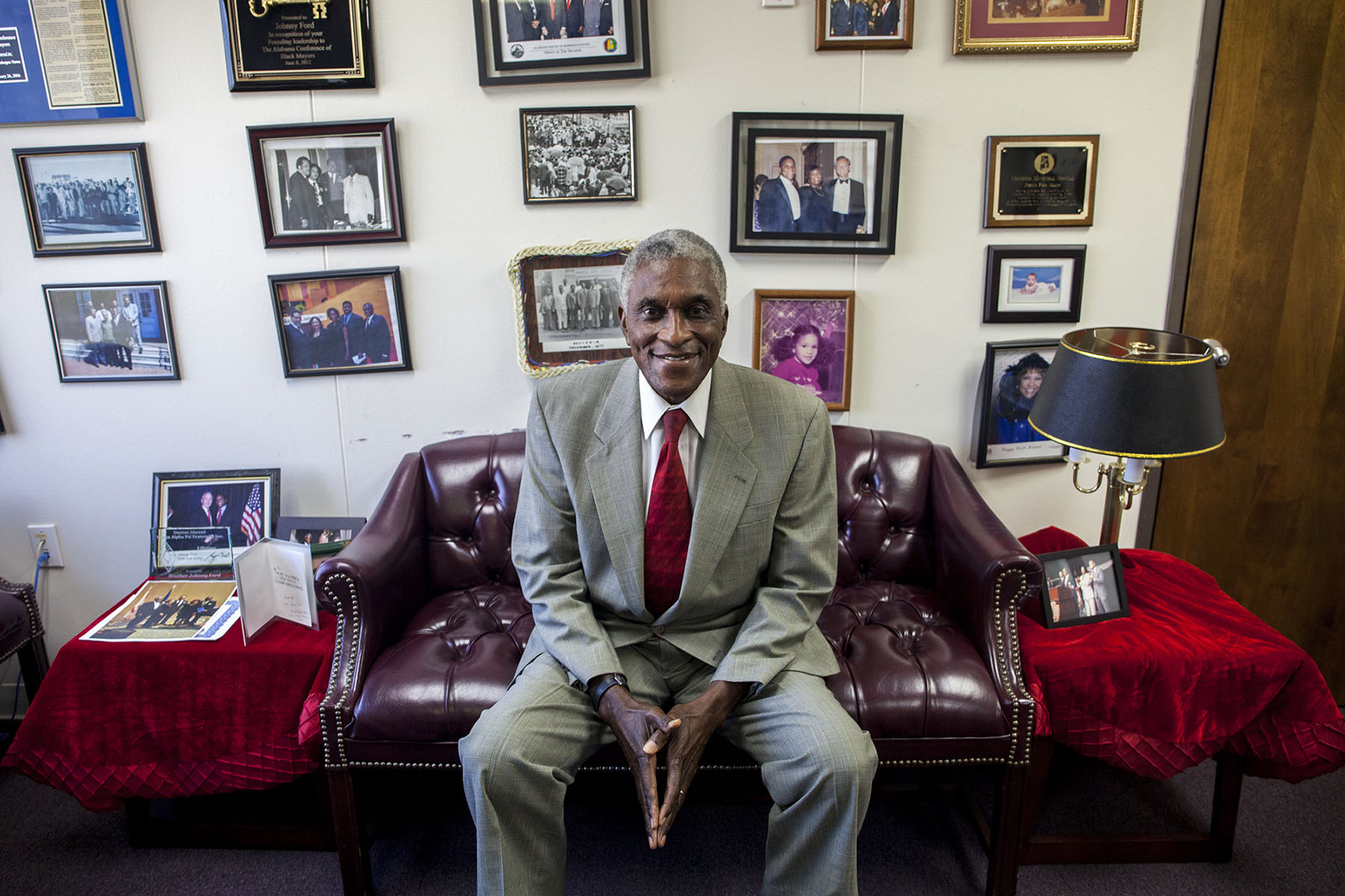 Tuskegee Mayor Johnny Ford sits in front of a wall of photographs in his office. Ford said the wall is a mix of professional and personal mementos. (Jeffrey Pierre/News21)