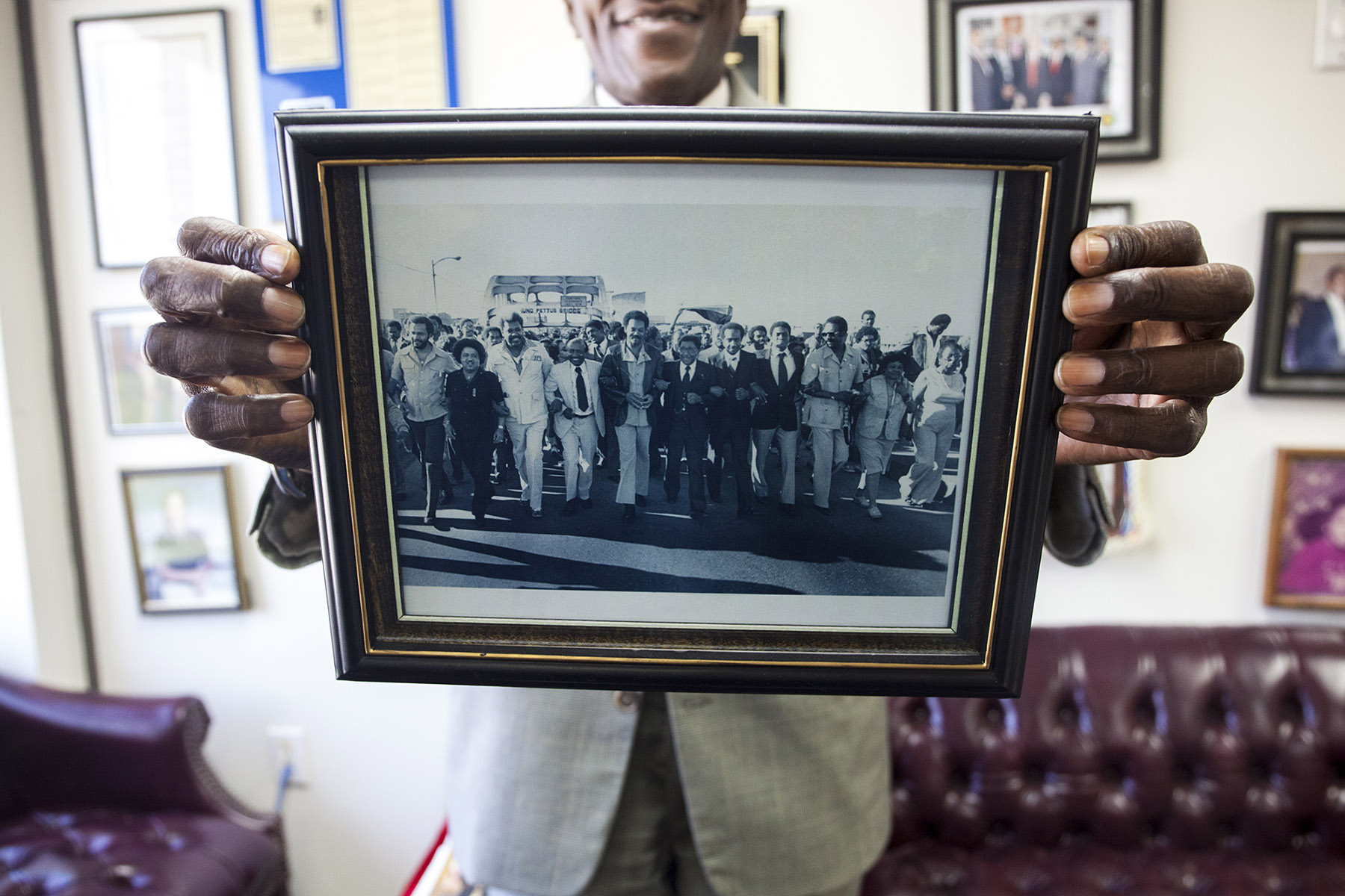 Ford holds up a photo of a commemorative march on the Edmund Pettus Bridge in 2004, but says voter discrimination has not stopped. (Jeffrey Pierre/News21)